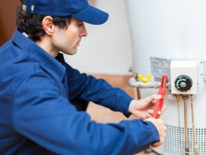 Technician repairing a hot water system not working with wrench in hand.