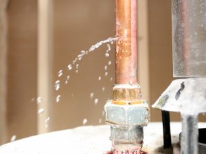 Water leaking from a copper pipe, which can contribute to low water pressure in homes and buildings.