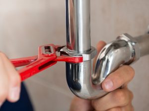 Plumber fixing a pipe to improve low water pressure in a residential home—how to fix low water pressure.