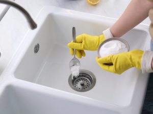 Baking soda being added to a drain, instead of boiling water down the drain.